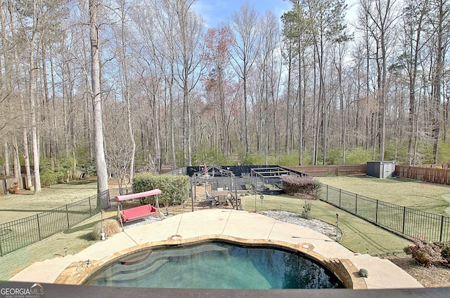 view of pool with a fenced backyard, a forest view, a yard, a fenced in pool, and a patio area