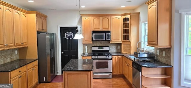 kitchen with stainless steel appliances, decorative backsplash, light wood-style flooring, a center island, and glass insert cabinets