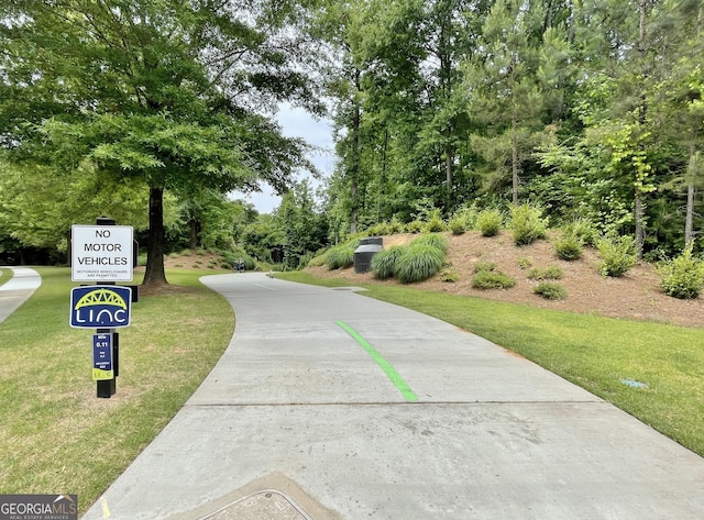 view of property's community featuring a lawn and concrete driveway