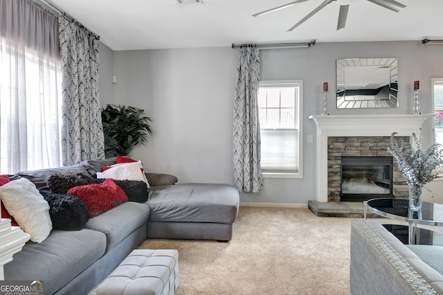 living room with a ceiling fan, healthy amount of natural light, carpet floors, and a stone fireplace