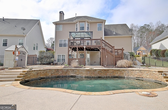 back of property featuring stairs, a wooden deck, fence, and a chimney