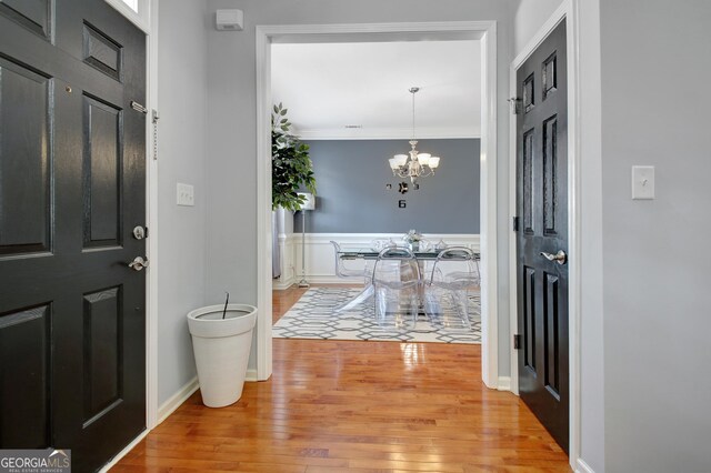 entrance foyer featuring an inviting chandelier, light wood finished floors, and ornamental molding