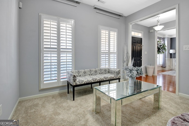 living area with plenty of natural light, carpet, visible vents, and baseboards