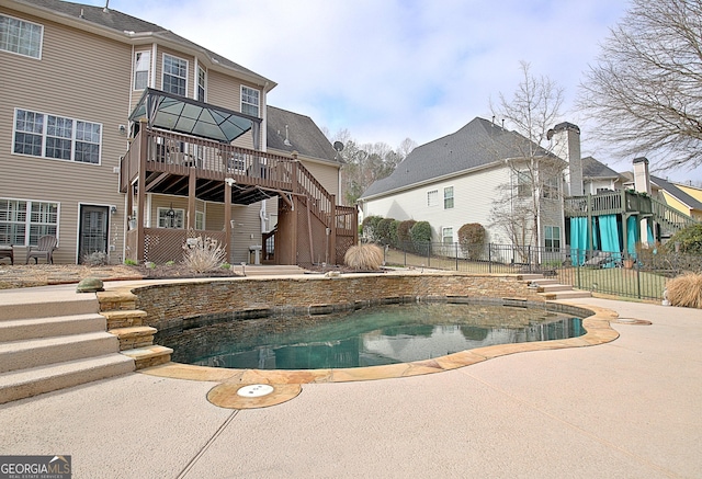 swimming pool with stairs, fence, a wooden deck, and a patio area