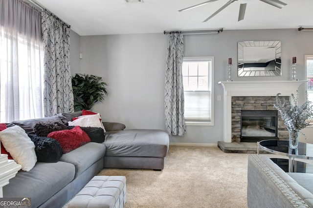 living room with visible vents, a ceiling fan, a stone fireplace, carpet flooring, and baseboards