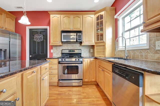 kitchen with visible vents, a sink, light wood-style floors, appliances with stainless steel finishes, and glass insert cabinets