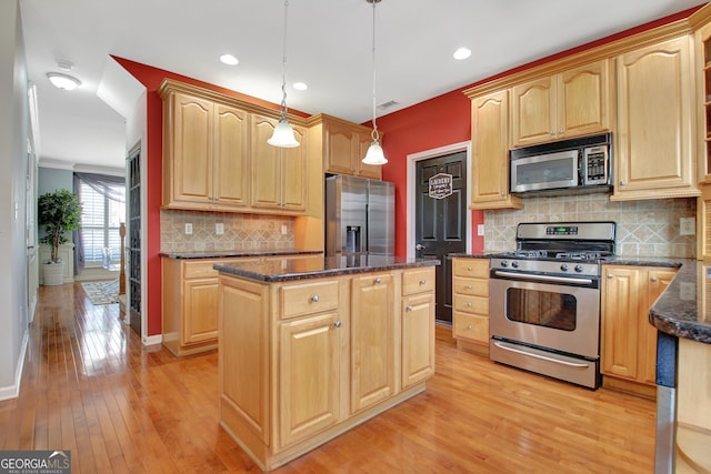 kitchen with light brown cabinets, appliances with stainless steel finishes, and a center island