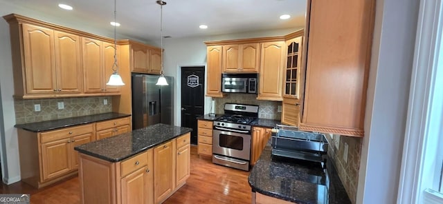 kitchen with appliances with stainless steel finishes, backsplash, a center island, wood finished floors, and recessed lighting