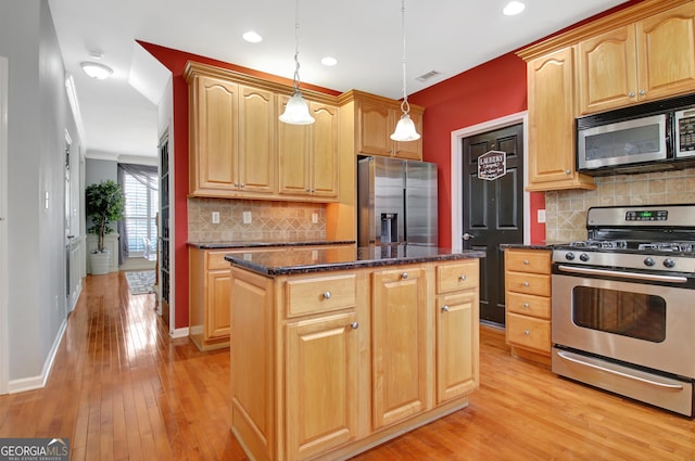 kitchen with visible vents, a center island, appliances with stainless steel finishes, light wood finished floors, and hanging light fixtures