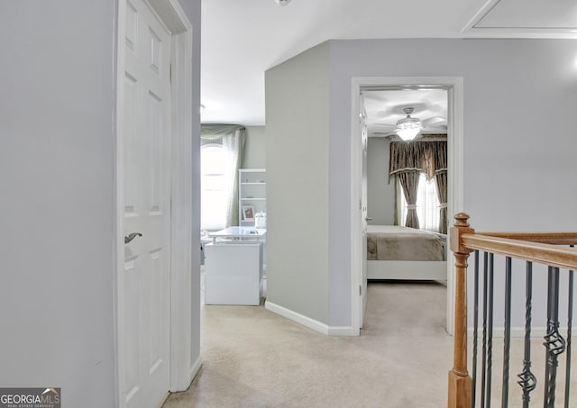 hall featuring light colored carpet and baseboards