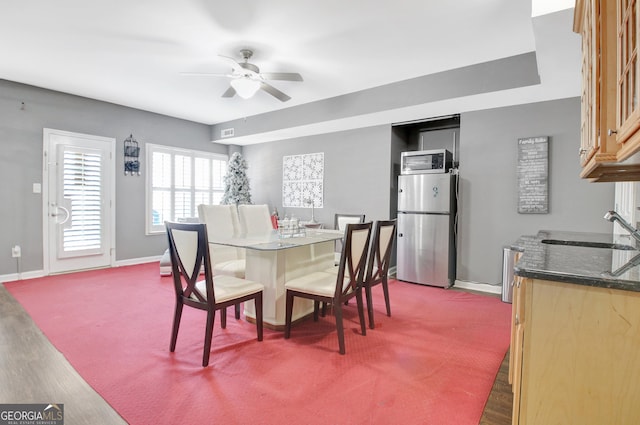 dining space featuring baseboards, ceiling fan, and dark colored carpet