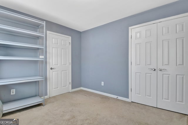 unfurnished bedroom with a closet, baseboards, and carpet floors