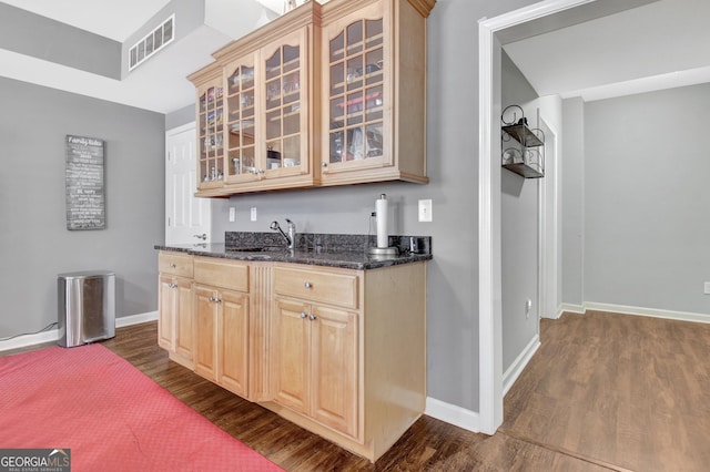 indoor wet bar with dark wood-style flooring and baseboards