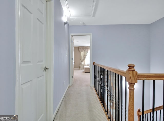 corridor featuring an upstairs landing, light colored carpet, attic access, and baseboards