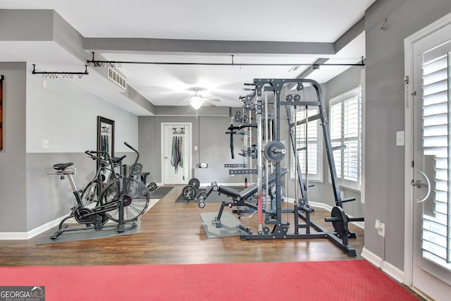 workout area featuring wood finished floors, a ceiling fan, and baseboards
