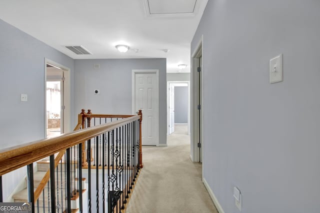 corridor featuring baseboards, an upstairs landing, visible vents, and light carpet