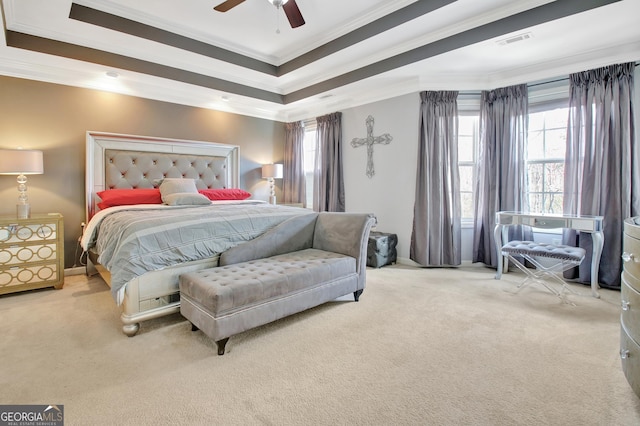 bedroom with visible vents, crown molding, a tray ceiling, carpet flooring, and a ceiling fan