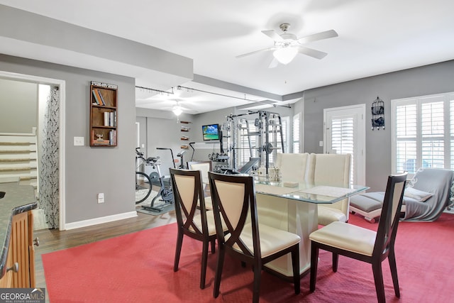 dining room with stairs, wood finished floors, a ceiling fan, and baseboards