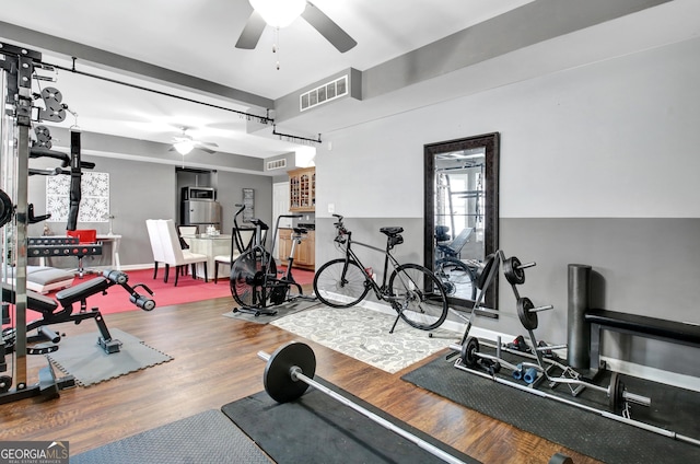 exercise room with baseboards, wood finished floors, visible vents, and ceiling fan