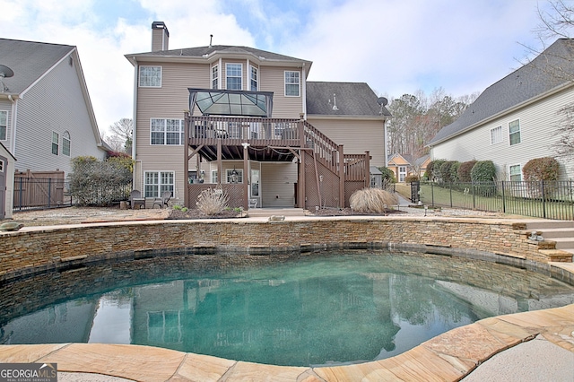 rear view of house featuring fence, a fenced in pool, a chimney, stairs, and a deck