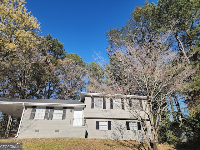 tri-level home with crawl space, a carport, and brick siding