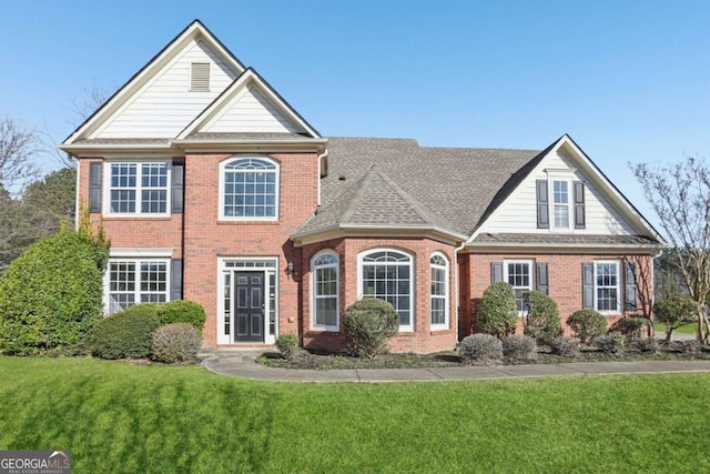 view of front of property featuring brick siding, a shingled roof, and a front yard