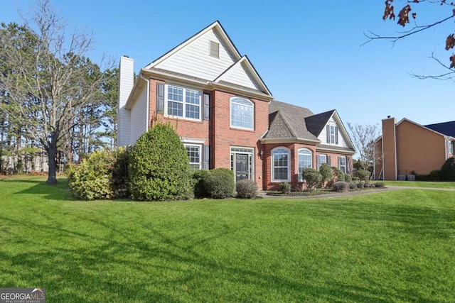 view of front of property with a front lawn, brick siding, and a chimney