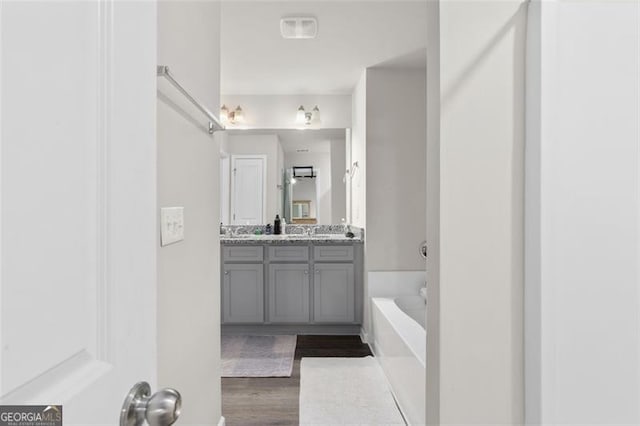 full bathroom featuring a washtub, vanity, and wood finished floors