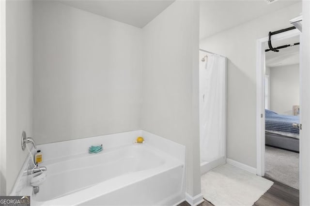 full bath with a shower stall, a bath, wood finished floors, and baseboards