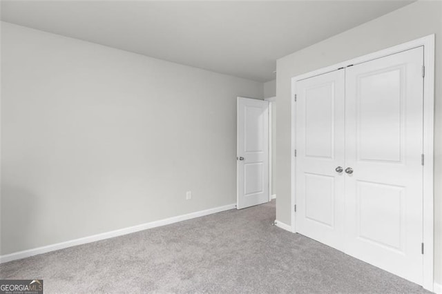 unfurnished bedroom featuring carpet flooring, baseboards, and a closet