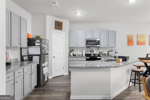 kitchen featuring light stone counters, visible vents, stainless steel appliances, and dark wood-type flooring