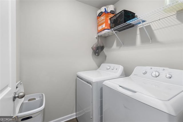 clothes washing area with baseboards, washing machine and dryer, and laundry area