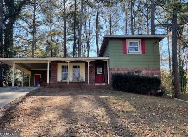 split level home featuring brick siding, a carport, a porch, and driveway