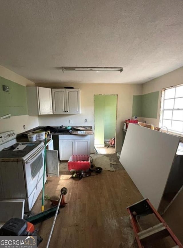 kitchen with a textured ceiling, wood finished floors, and white range with electric cooktop