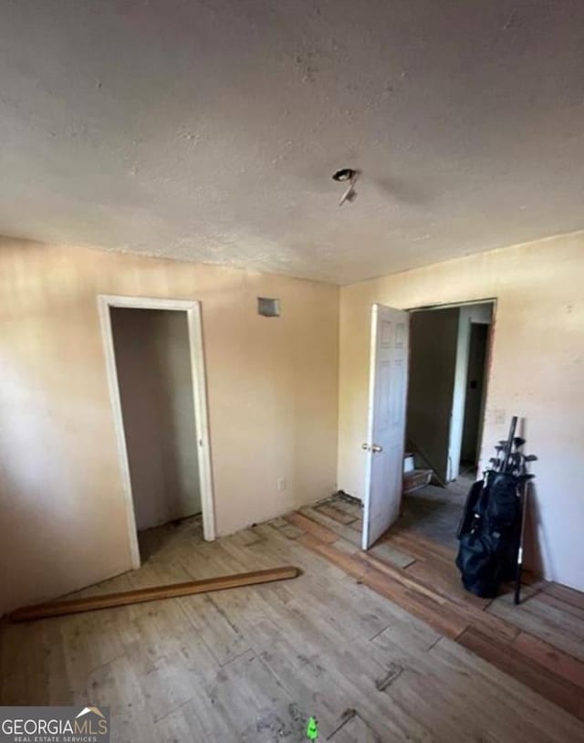 unfurnished bedroom featuring a textured ceiling and wood finished floors