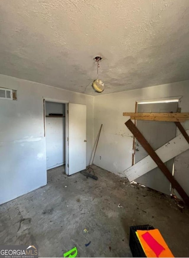 interior space featuring visible vents, a textured ceiling, and unfinished concrete flooring