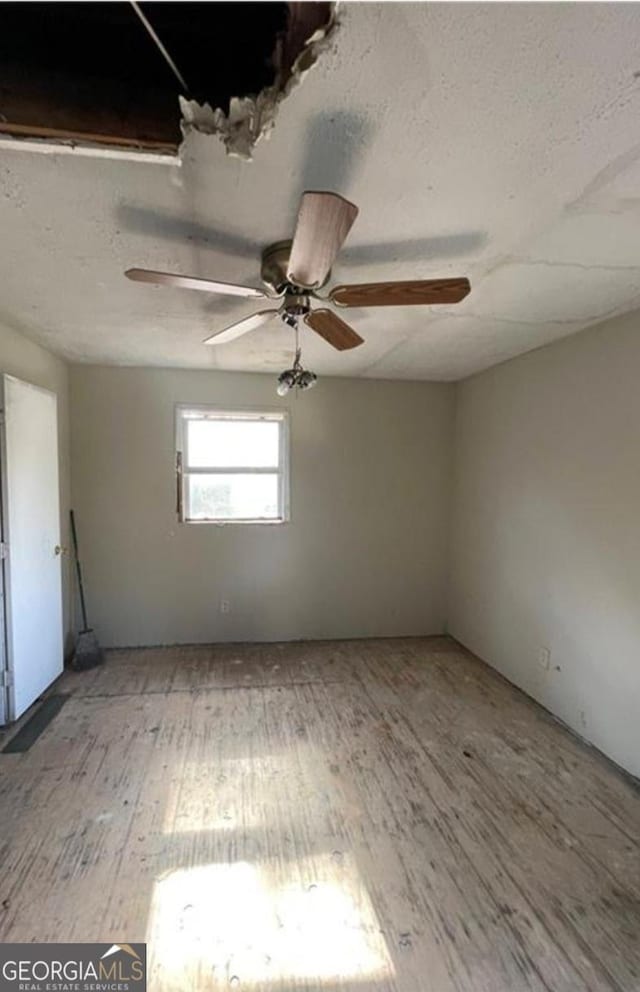 empty room with a ceiling fan, wood finished floors, and a textured ceiling