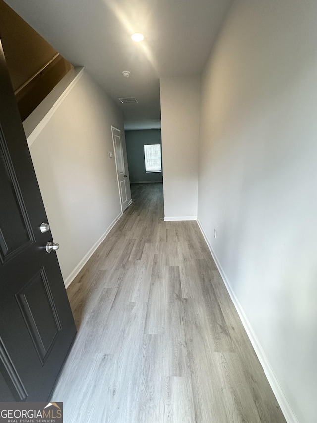 corridor featuring light wood-type flooring and baseboards