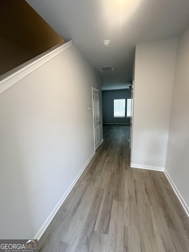 hallway featuring wood finished floors, visible vents, and baseboards