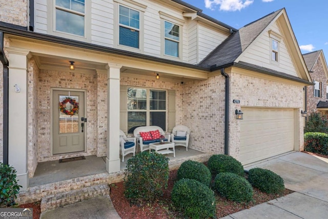 entrance to property with a garage, brick siding, a porch, and driveway