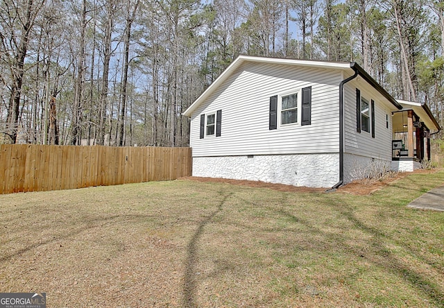 view of side of home with crawl space, a yard, and fence