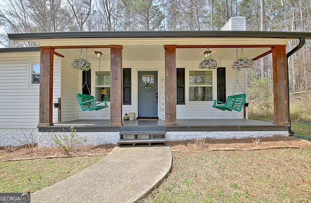 entrance to property featuring a porch and a chimney