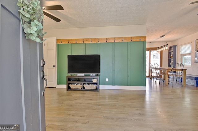 living room with a textured ceiling, light wood-style flooring, and a ceiling fan