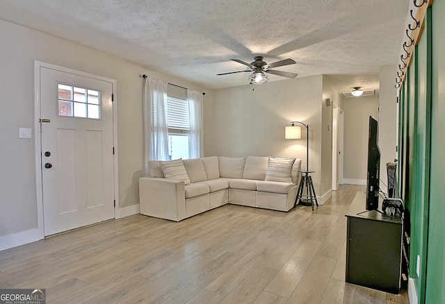 unfurnished living room with baseboards, a textured ceiling, light wood-style flooring, and a ceiling fan