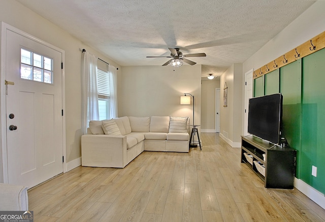 unfurnished living room featuring baseboards, a textured ceiling, ceiling fan, and light wood finished floors