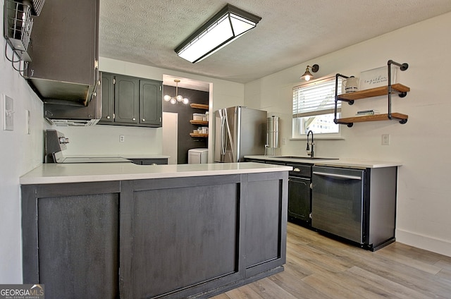 kitchen with a peninsula, open shelves, a sink, light wood-style floors, and appliances with stainless steel finishes