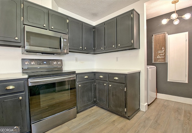 kitchen featuring light wood-type flooring, washer / clothes dryer, a textured ceiling, stainless steel appliances, and light countertops