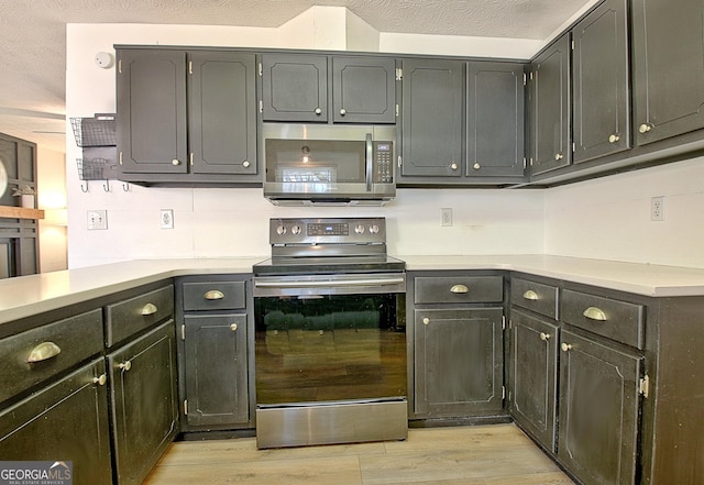 kitchen featuring light countertops, light wood finished floors, appliances with stainless steel finishes, and a textured ceiling