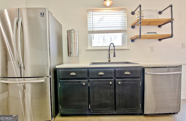 kitchen featuring a sink, appliances with stainless steel finishes, dark cabinetry, and light countertops