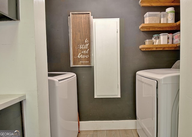 washroom with baseboards, wood finished floors, washing machine and dryer, and laundry area